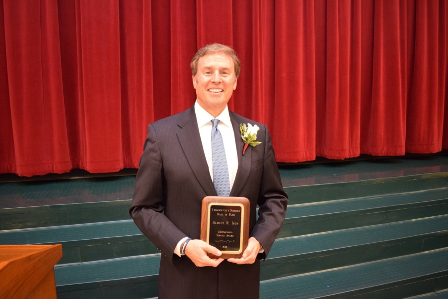 man holding a plaque in front of a red statge curtain